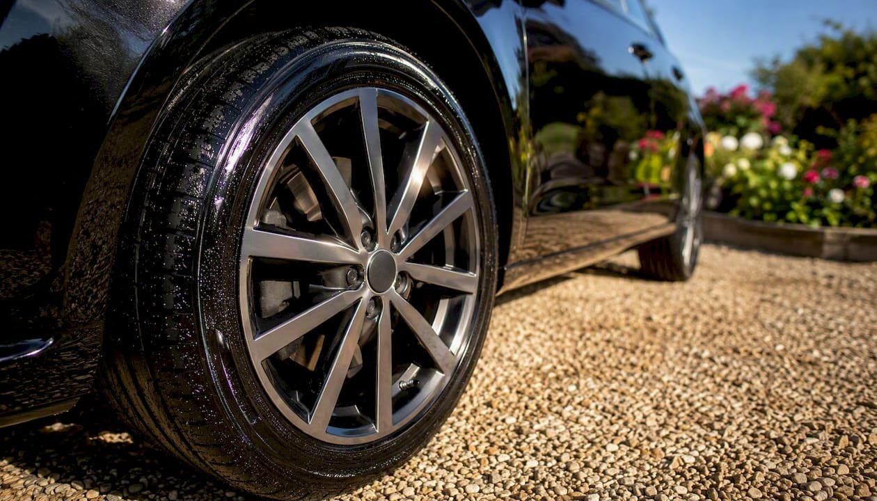 Shiny tyre and wheel on wet driveway