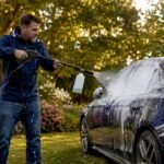 Man applying pre-wash foam on car with foam cannon