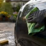Hand wiping car door to remove water spots