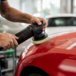 Hands polishing car panel to remove coating