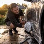 Hands washing car paint with ceramic shampoo foam