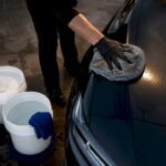 Two bucket wash beside glossy paint panel