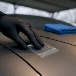 Hand performing baggie test on car paint