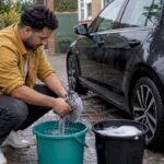 Car owner rinses mitt between two wash buckets